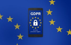 Symbolbild: ein Smartphone zwischen zwei EU-Flaggen. Auf dem Display ist der Schriftzug "GDPR" über einer EU-Flagge zu sehen, in deren Mitte ein Schlosssymbol abgebildet ist. Darunter steht "EU Data Protection Regime"
